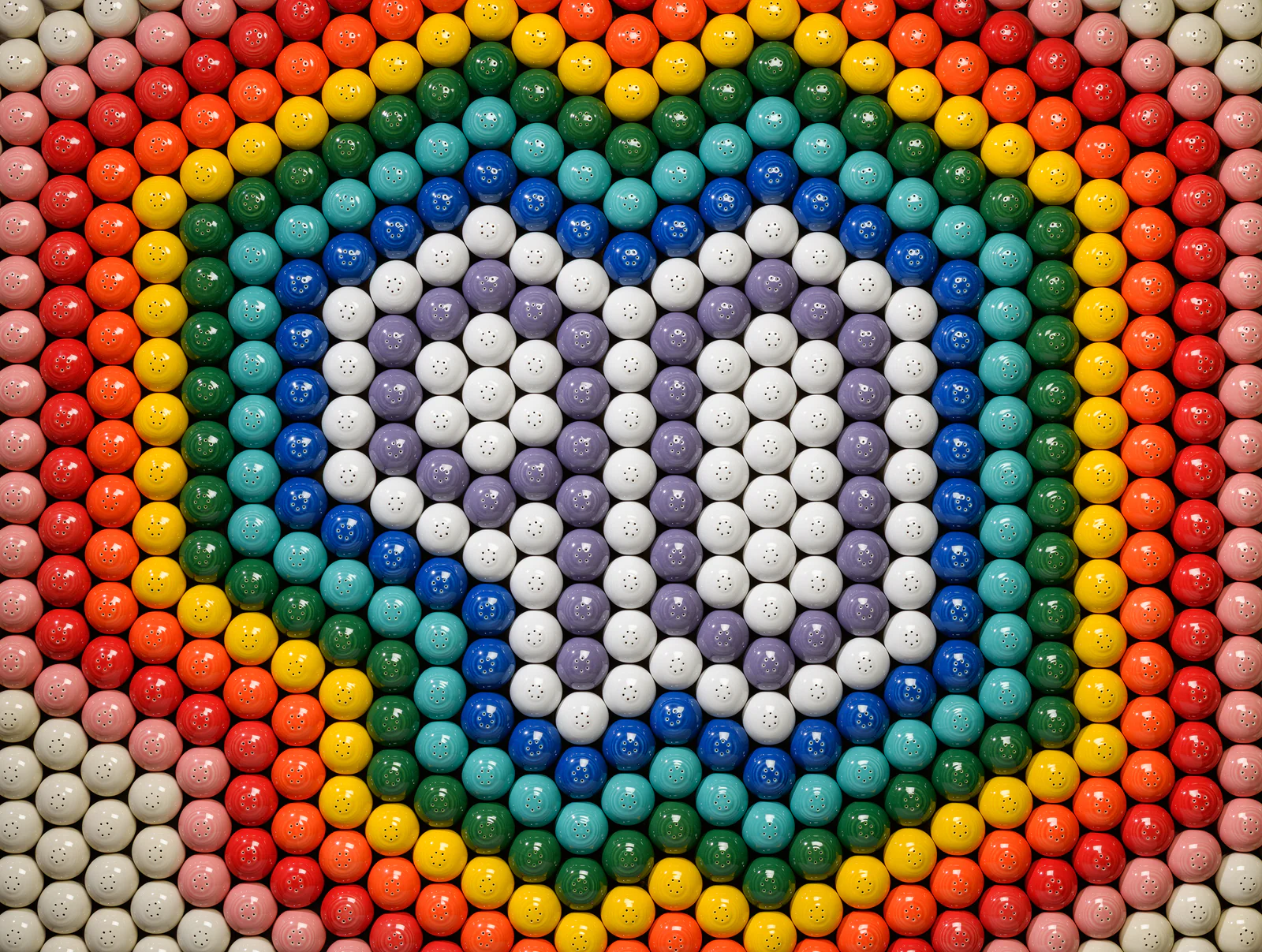 A colorful arrangement of round objects forming a heart shape, surrounded by a rainbow pattern.